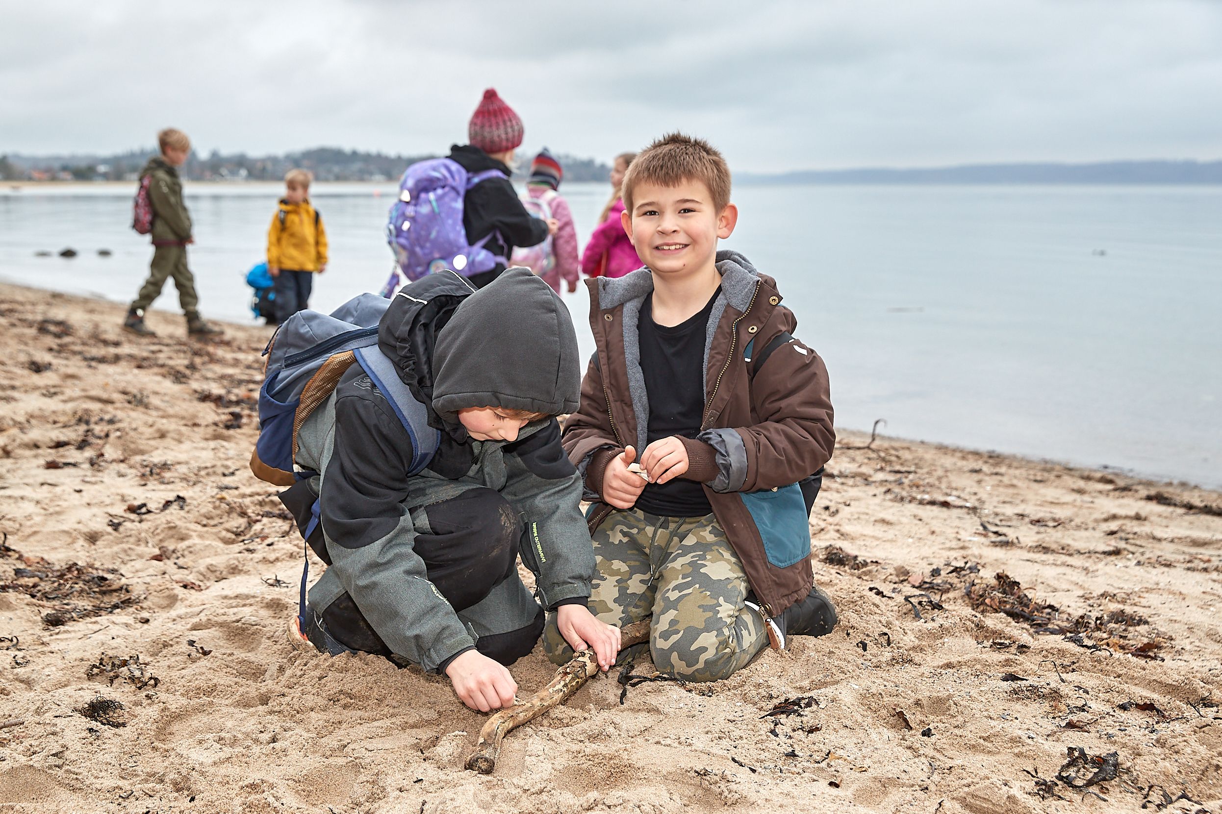 0. - 1. klasse på stranden. To elever smiler